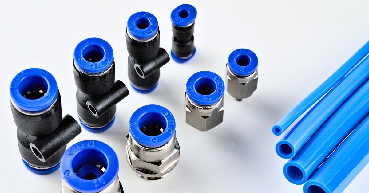 An assortment of silver and black pneumatic fittings on a white background with blue pipes in varying widths.