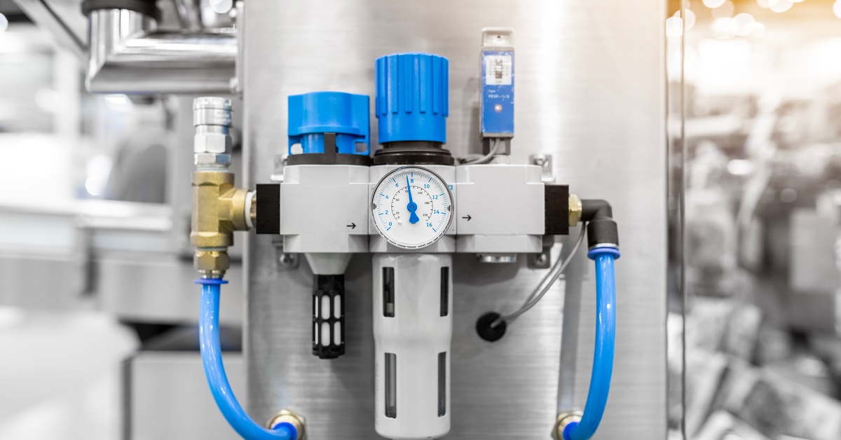 A pneumatic air unit with a pressure gauge, blue knobs, transparent filter bowl, blue hoses, and metal panel mount.
